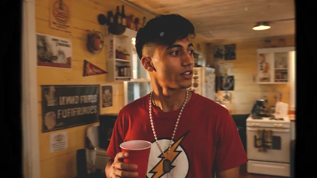 Personagem A de camiseta do Flash na cozinha da casa