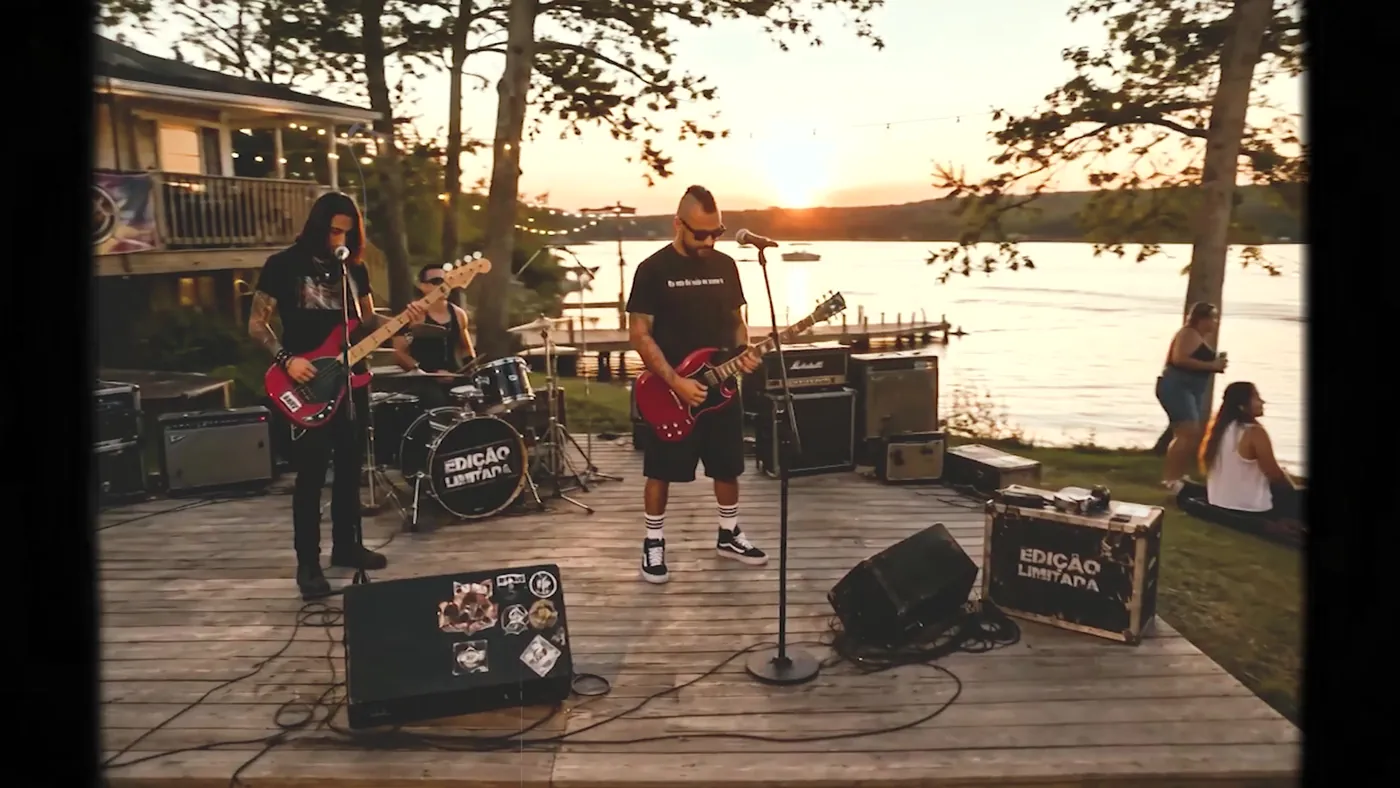 Banda tocando no deck de madeira à beira do lago durante o pôr do sol